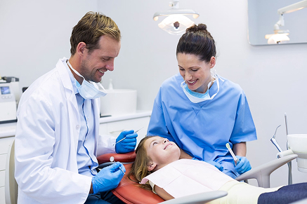 Dentist and dental hygienist caring for child patient in clinic chair