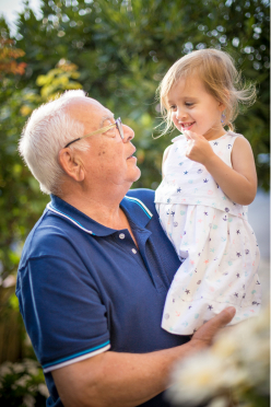 Grandfather holding young granddaughter outside in rural Alberta sunshine