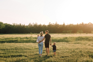 Young family walking through sunny farm field at sunset near Westlock Alberta