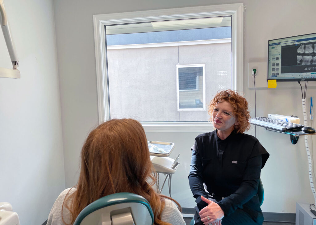 Dental hygienist at Westlock Family Dental smiling and interacting with a patient in a clinical dental treatment room in Westlock, Alberta